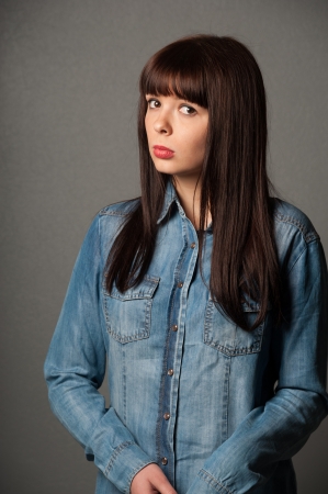 Portrait of serious sad pretty girl on gray の写真素材