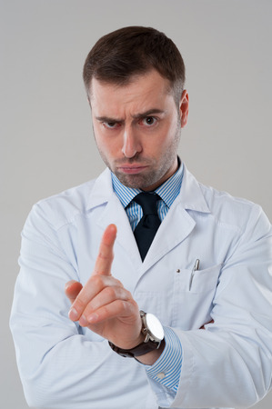 Portrait of doctor mature male with finger in air isolated on grey backgroundの写真素材