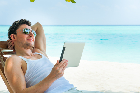 Man relaxing at the beach with tablet, laptop. Maldives island, ocean viewの写真素材