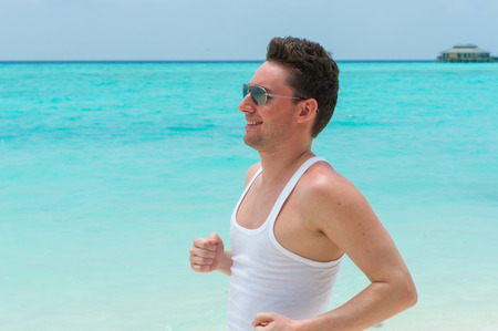 Man running on the beach at the background of turquoise water of the ocean, Maldives island, sport manの写真素材
