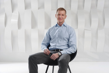 Business man sits on chair against background of abstract modern urban interiorの写真素材
