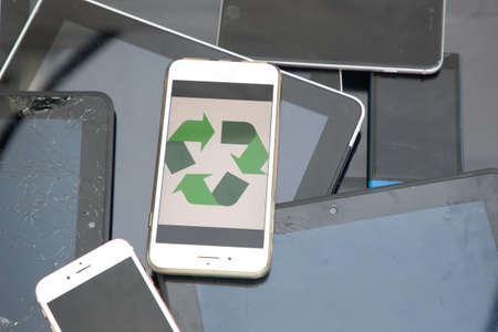 mobile phone with recycling logo on top of pile of tablets and phonesの写真素材