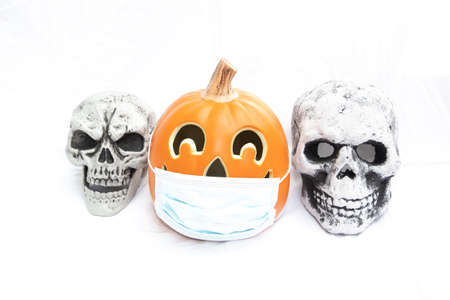 Covid Halloween pumpkin with a face mask and skeleton heads either sideの写真素材