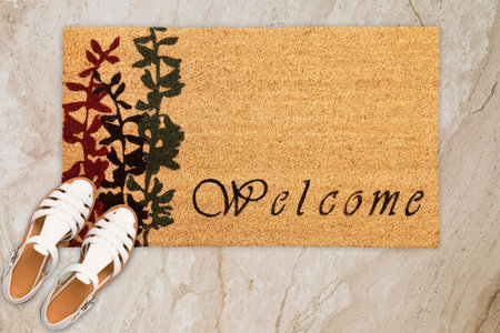 Designer Welcome Entry Doormat Placed on Marble Floor with White Ladies Sandlesの写真素材