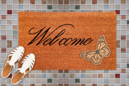 Designer Welcome Entry Doormat Placed on Square Marble Floor with White Ladies Sandlesの写真素材