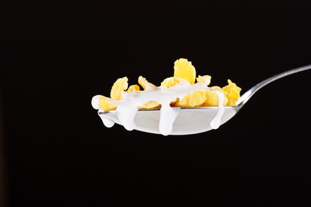 Corn flakes on the spoon with milk の写真素材