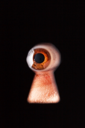 Eye looking through a keyholeの写真素材