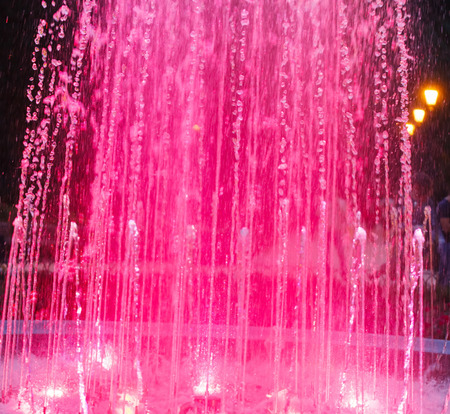 Colored water fountain at nightの写真素材