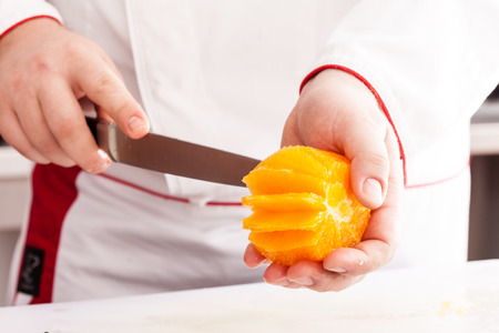 chef cutting orangeの写真素材