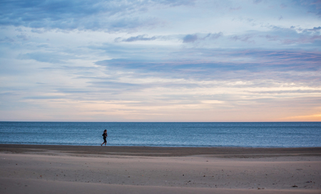 Valencia, Spain - JAN 6, 2016: Women running on the beach with the sea in the backgroundの写真素材