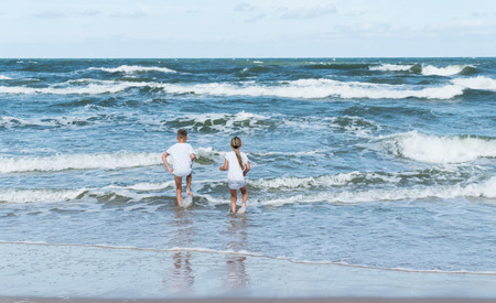 boy and girl on the sea wavesの写真素材
