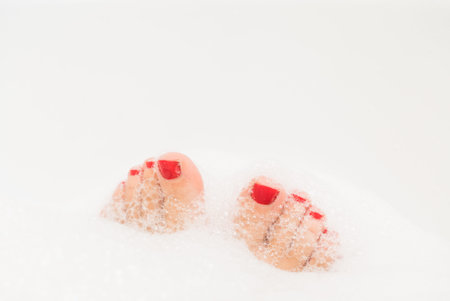 Feet with red nails soaking in spa bath