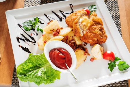 Roasted chicken breasts stuffed with mushrooms, pepper and cheese, garnished with potatoes and tomato sauceの写真素材