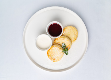 Cottage cheese pancakes sour cream and jam,  syrniki on white backgroundの写真素材