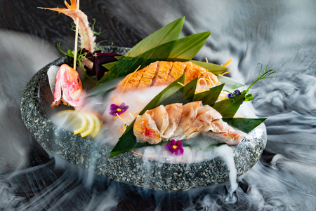 Japanese foods sashimi (raw sliced fish, shellfish or crustaceans) with smoke on the blackの写真素材