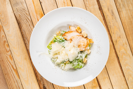 Fresh caesar salad in white plate, woodenの写真素材