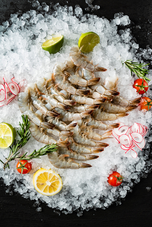 raw shrimps with lime and rosemary on the iceの写真素材