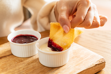 woman eating baked brushwood dessert with saucesの写真素材