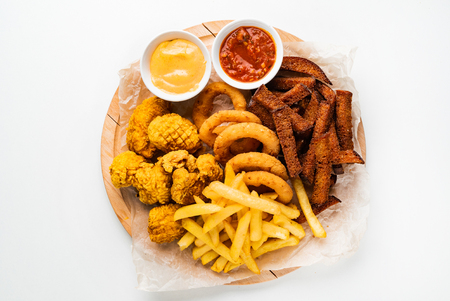 The beer plate with spicy chicken wings, calamari rings, fries onion rings, cheese balls, breaded, ketchup and mustard sauceの写真素材