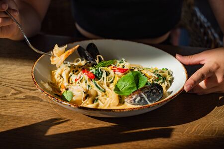 woman eating seafood pasta in the cafeの写真素材