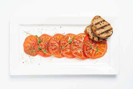 tomato carpaccio with toasts on white plateの写真素材