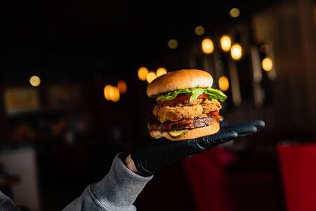 man in black gloves eating burger in the restaurantの写真素材