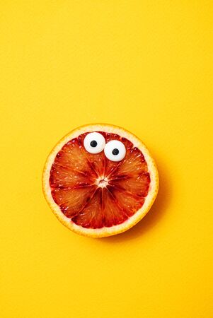 funny blood orange on the yellow backgroundの写真素材