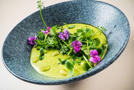 green pea cream soup with edible flowersの写真素材