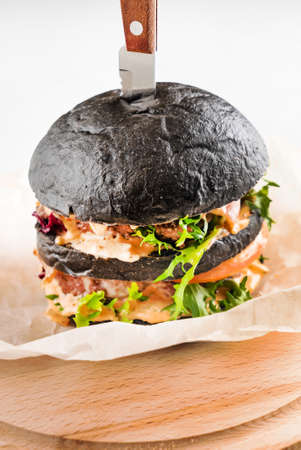 An appetizing black hamburger on the wooden backgroundの写真素材