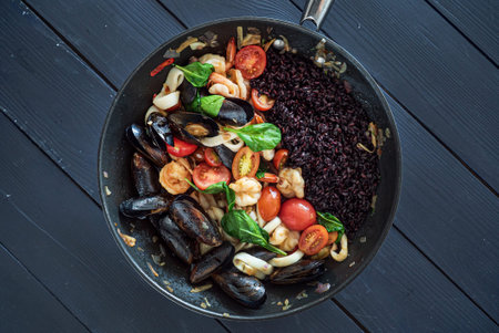 paella with black rice and seafoodsの写真素材