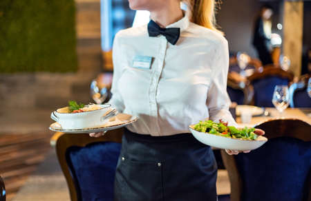 Waiter carrying plates with meat dish on some festive eventの写真素材