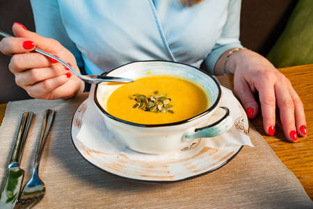woman eating pumpkin cream soupの写真素材