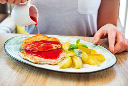 woman eating pancakes with applesの写真素材