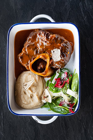 Close up of tasty roasted veal gremolata with tomato sauce and parsley in plate on tableの写真素材