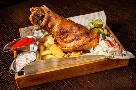 Traditional gourmet german snack of roasted potatoes, grilled pork ribs with fried vegetables, shank and beer in a pan on a grill panel.の写真素材