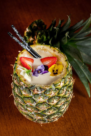 Pina Colada in Pineapple with strawberries and straws
