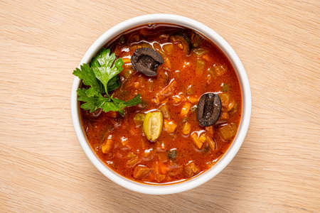 Spicy solyanka soup topped with pork sausages, cucumber and lemon.の写真素材