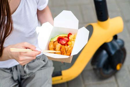 woman with scooter eating asian foodの写真素材