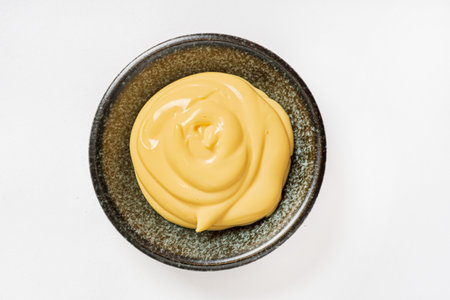 Mustard sauce in a bowl isolated on white background. Top view.の写真素材