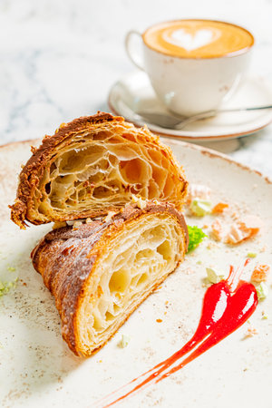 Croissant with cream and coffee cup on white background, close upの写真素材