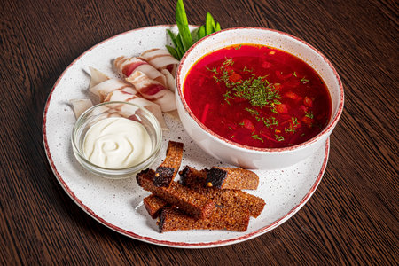 Red borscht with bread and sour cream on a wooden backgroundの写真素材