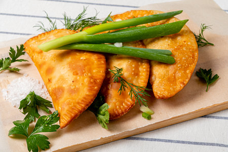 chebureks with fresh herbs on wooden trayの写真素材