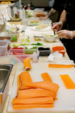 Chef preparing sushi rolls on the counter in a Japanese restaurant.