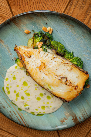 Grilled salmon fillet with broccoli and cream sauce on blue plate