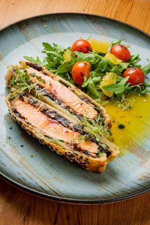 salmon pie with arugula salad on tableの写真素材