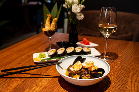 Delicious seafood dish featuring shrimp and mussels, elegantly displayed alongside sushi and a refreshing glass of white wine. A cozy atmosphere creates the perfect dining experience.の写真素材