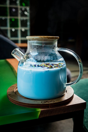 A glass pitcher filled with a vibrant blue beverage sits on a wooden coaster, surrounded by a tranquil atmosphere.の写真素材