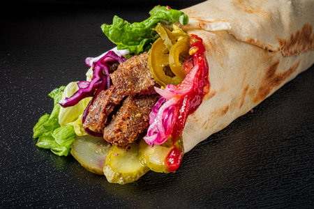 A tasty wrap packed with juicy meat, fresh greens, pickles, and colorful veggies awaits!の写真素材