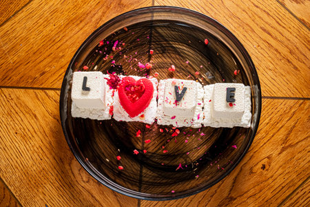A delightful dessert showcases the word love with a heart shape, adorned with colorful petals.の写真素材