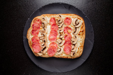A warm flatbread topped with savory salami and sliced mushrooms awaits in a cozy kitchen setting.の写真素材